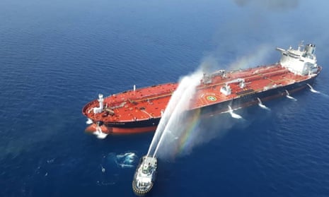 a boat douses a tanker on fire in the gulf of oman