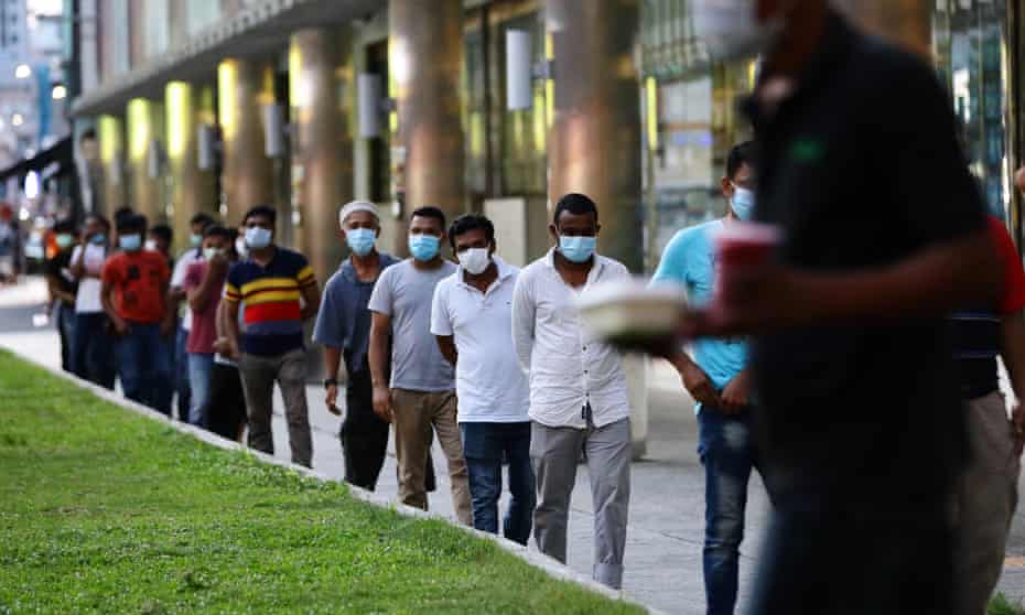 Foreign workers wearing protective masks queue for free meals in Singapore