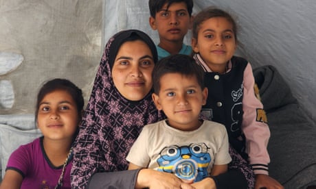 A woman wearing a scarf surrounded by four children