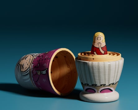 A small wooden doll child with her hand held to her mouth, nested inside other wooden dolls