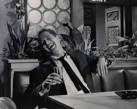 Paul Newman in a scene from the movie The Young Philadelphians. Newman is in a restaurant-like setting, holding a glass and laughing uproariously.