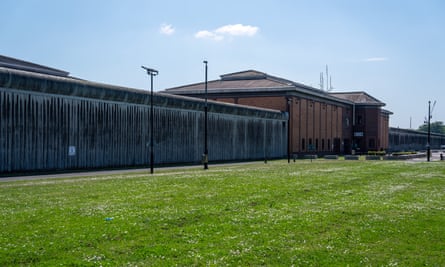 HMP Belmarsh, in London, pictured on 20 May 2024: a tall wall is seen across a stretch of mowed grass in front of austere brick buildings. Surveillance cameras monitor the wall, gateway and entrance to a building.