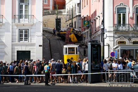Onlookers gather behind a police line to watch as officials inspect the site of the accident