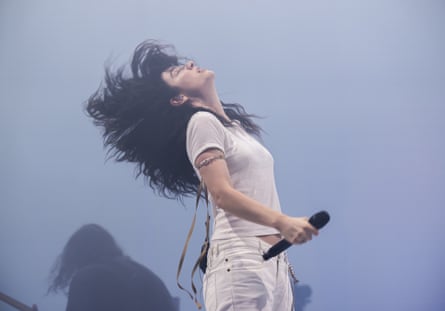 Lorde throwing her head back, with a microphone in her hand