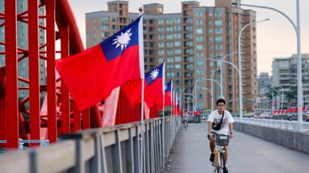 A person riding a bike past a row of red and blue Taiwan flags