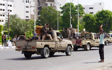 Men with guns ride on a flatbed truck
