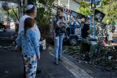 बच्चे को ले जा रही एक महिला एक युवा लड़की का हाथ पकड़कर एक आदमी से बात कर रही है।