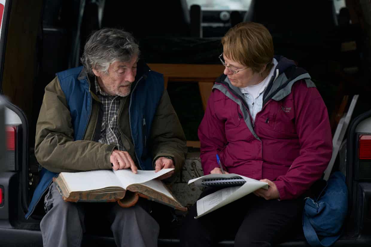 Andrew Bennett and Monica Dolan, who play Aidan and Catherine Corless, look at a large book and documents in a scene from the film