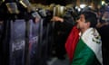 A protester draped in Mexico flag confronts police