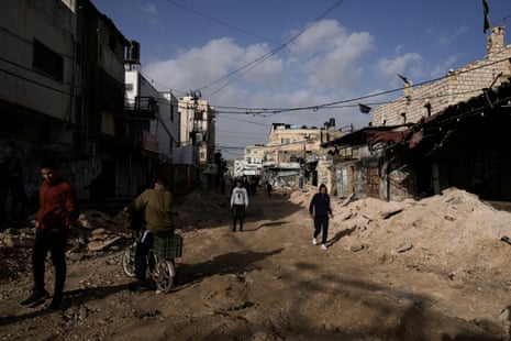 Palestinians walk on a damaged road after an Israeli army operation in Jenin refugee camp, 26 November.