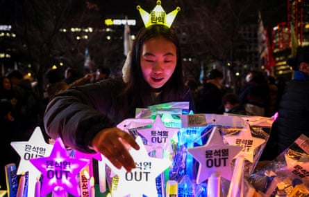 A shopkeeper sells light sticks that read ‘Yoon Suk Yeol OUT’ during a rally in Seoul on Tuesday.