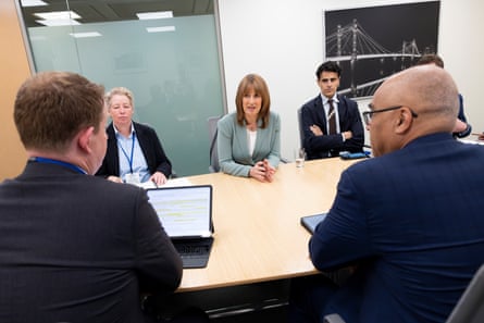Rachel Reeves, wearing a turquoise suit, sits at a meeting room table with other officials