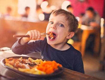 A boy having fun eating a meal in a restaurant.