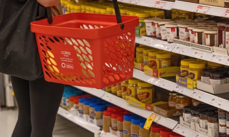 A person carrying a shopping basket in a Coles supermarket