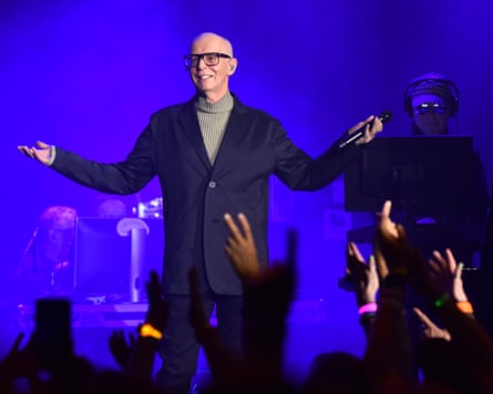 Neil Tennant onstage holding his arms wide