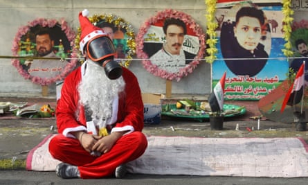 An Iraqi demonstrator in Tahrir Square with a gas mask on and wearing a Santa suit