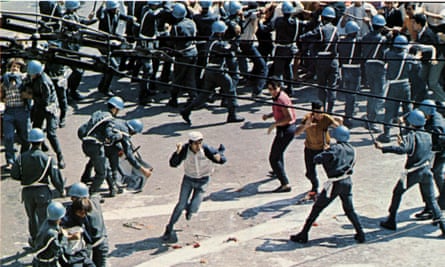 A man waving both fists runs through a phalanx of riot police, seen from above