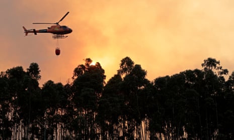 A helicopter combats a forest fire in Monchique