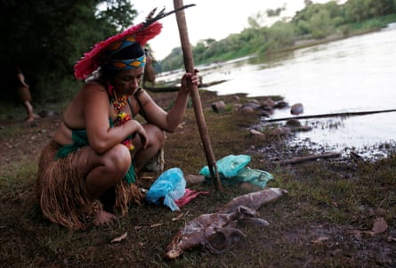 An Indigenous woman looks at dead fish near Paraopeba river in Sao Joaquim de Bicas, Brazil, after a tailings dam collapsed in January 2019.