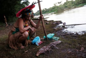 Una mujer indígena mira peces muertos cerca del río Paraopeba en el Cerrado.