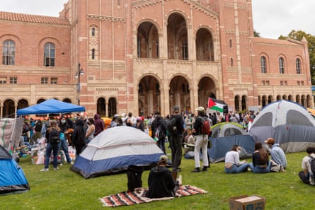 People and tents on a lawn in front of pink building