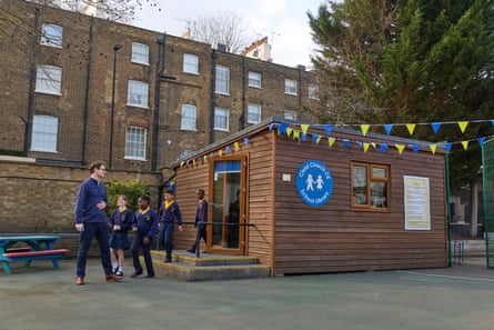 A teacher and schoolchildren standing outside a wooden library