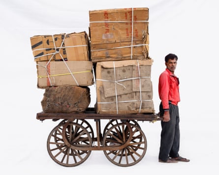 Courier Bally in Ujjain, Madhya Pradesh, India. He is pulling a trolley with large packages piled high on it.