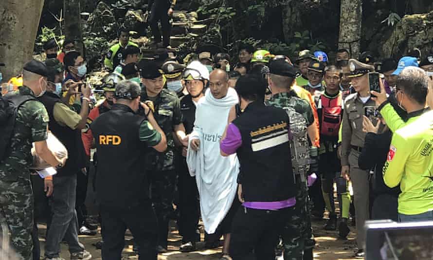 Rescuers help Phra Manas, centre, walk out of the cave on Wednesday.