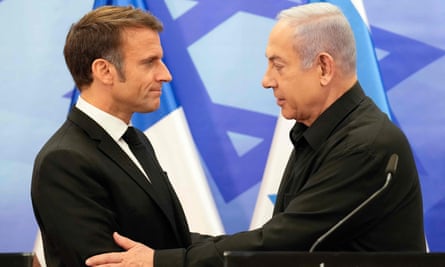 The Israeli prime minister, Benjamin Netanyahu, (right) greets Emmanuel Macron with Israeli flag in background