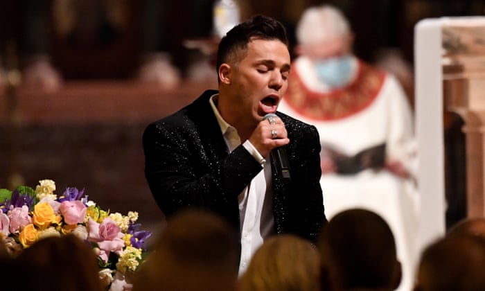 Anthony Callea sings into a microphone with a bouquet of flowers in the foreground