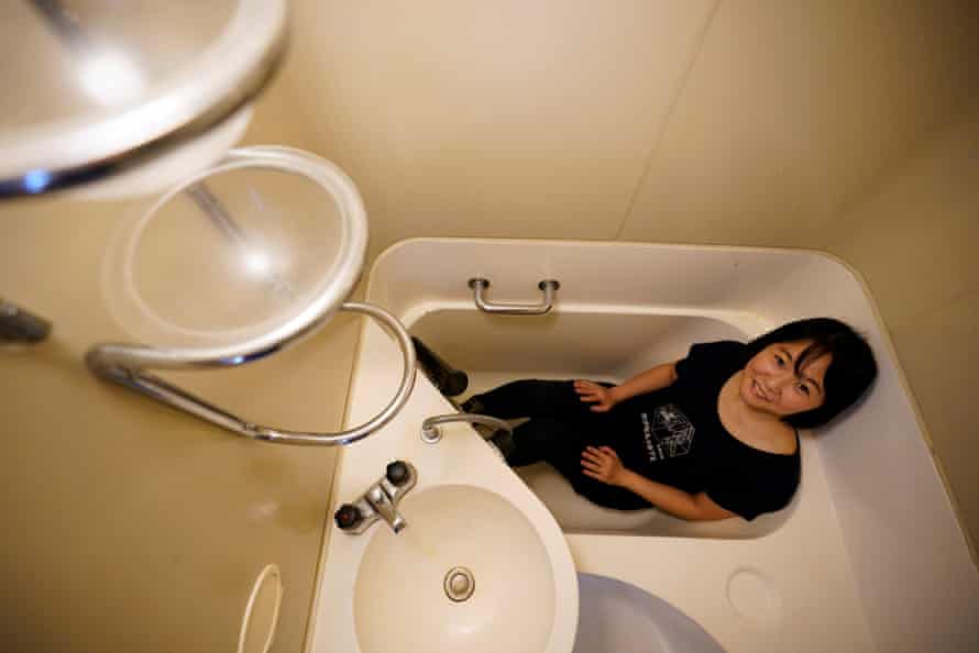 Decaying but beloved, Tokyo’s Capsule Tower faces uncertain future | Japan 4 Former resident Akiko Ishimaru sits in the bathtub of a capsule at the Nakagin Capsule Tower