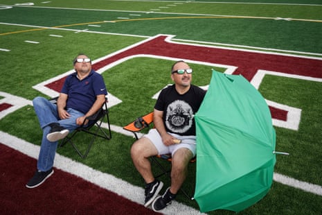Joe Solis, left, and his brother Ric Solis set up on the 50-yard line to watch the total solar eclipse at Eagle Pass Student Activities Center, in Eagle Pass, Texas.