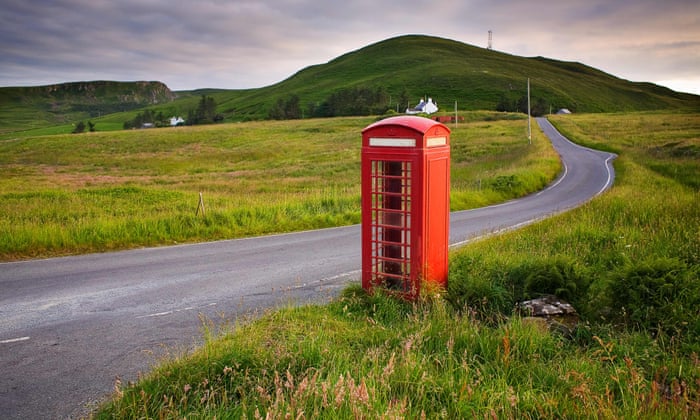 wide shot of red telephone boxes abandoned in a rural setting