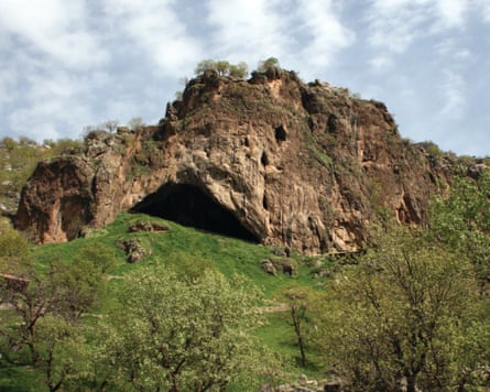 A cave on a hill of grass and trees