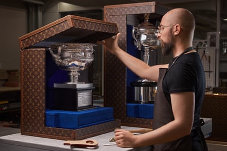 A man opens a Louis Vuitton trunk with a trophy in it