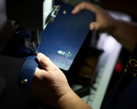 Blue leather being guided through a sewing machine at Ettinger’s workshop.