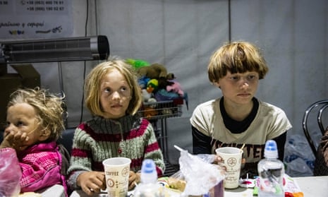 Men, women and children eat and drink at a food tent in Zaporizhzhia catering for evacuees after having arrived from Mariupol.