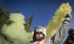 A reveller covered in flour holds a smoke bomb
