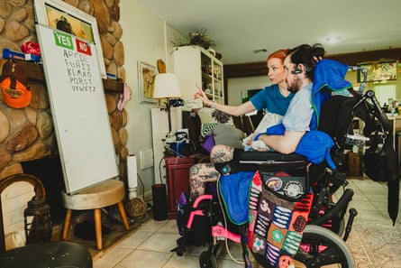 A therapist directs a patient to a whiteboard with “yes” and “no” and the alphabet on it