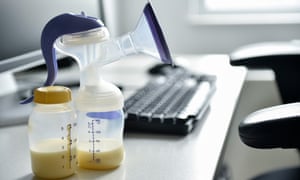 Breast pump and bottle of breast milk near computer