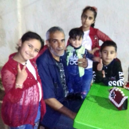 A family photo of Ashraf al-Ghussain and his four children sitting beside a table