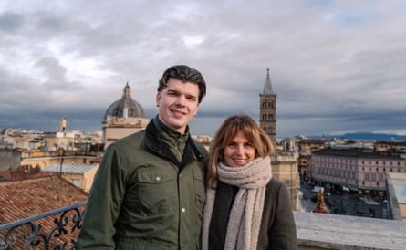 Mother and son on a rooftop, arms around each other’s shoulders, with Roman cityscape in the background