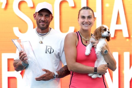 Frangulis connected nan left, dressed successful achromatic pinch a achromatic cap, and Sabalenka connected nan right, dressed successful pinkish tennis cogwheel and holding a brownish and achromatic puppy
