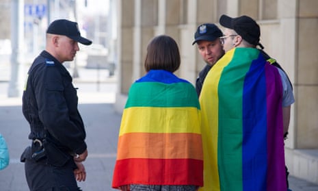 Police officers with two people wearing rainbow flags