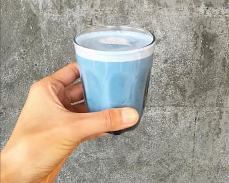 A hand holding a baby-blue, foamy drink