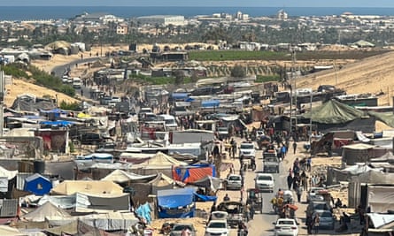 Convoys of vehicles on a road surrounded by tents.