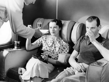 A couple enjoys cocktails in the smoking lounge of the new Imperial Airways Empire flying boat passenger plane, London c. 1936.
