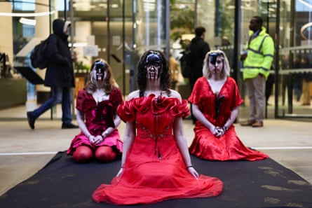 three protesters kneeling with what appears to be oil dripping down their faces