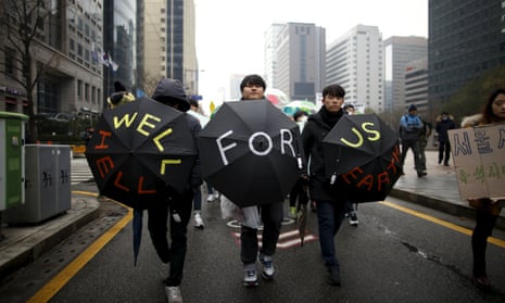 Participants holding umbrellas with the message “Well for us, Hell for earth” march in Seoul.
