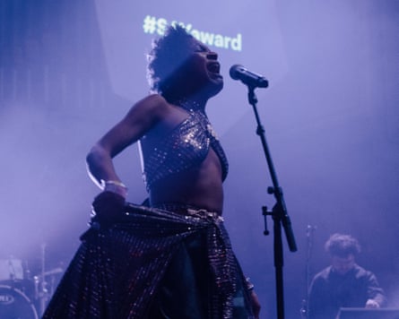 Bel sings on stage into a microphone